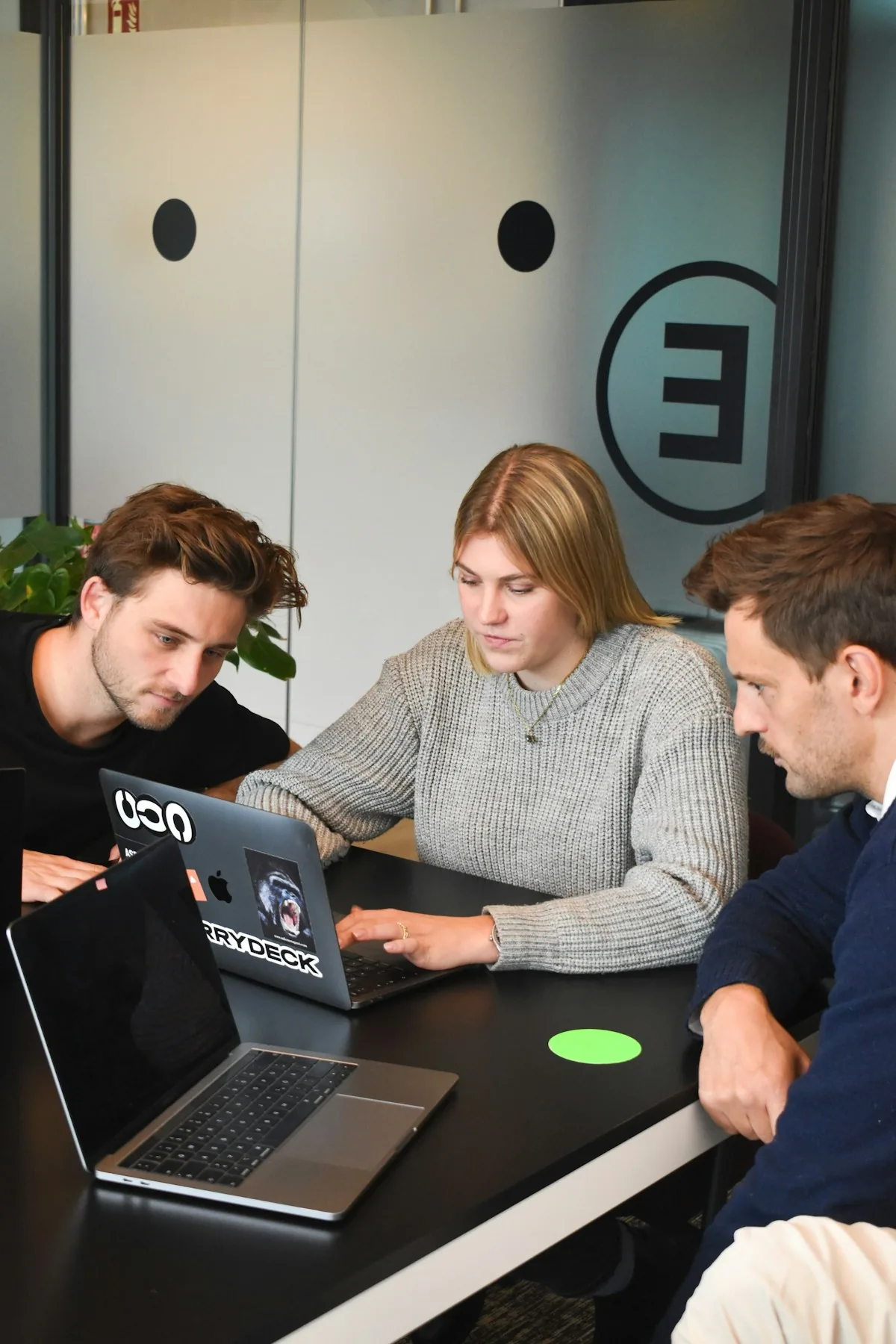 Three people collaborating around a laptop discussing a project